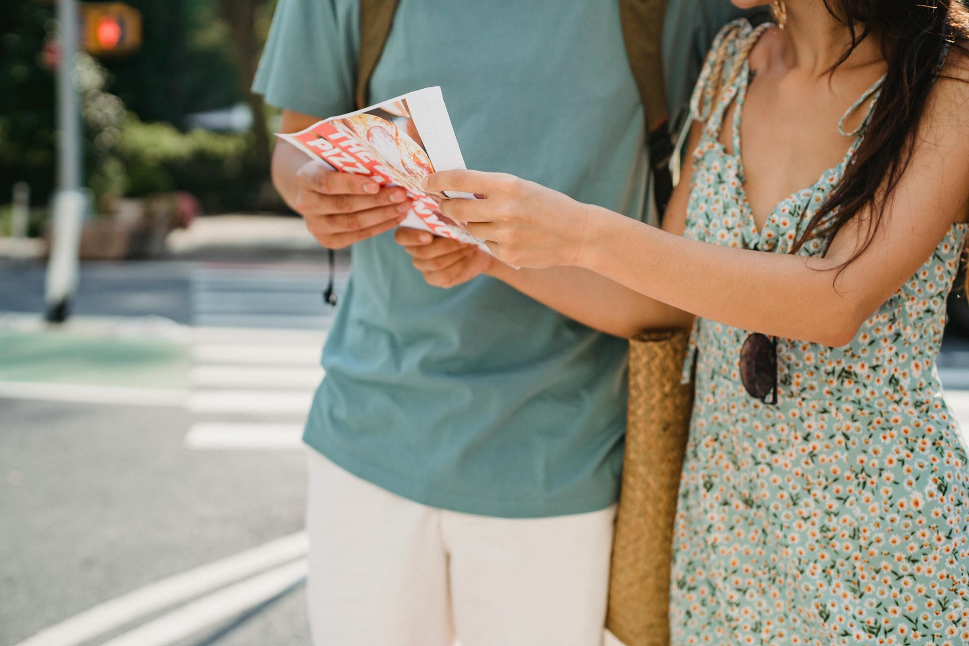 Crop anonymous couple searching direction in map while sightseeing together in city center during trip