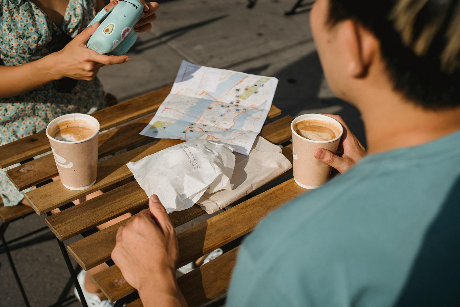 Young couple drinking coffee while using instant photo camera