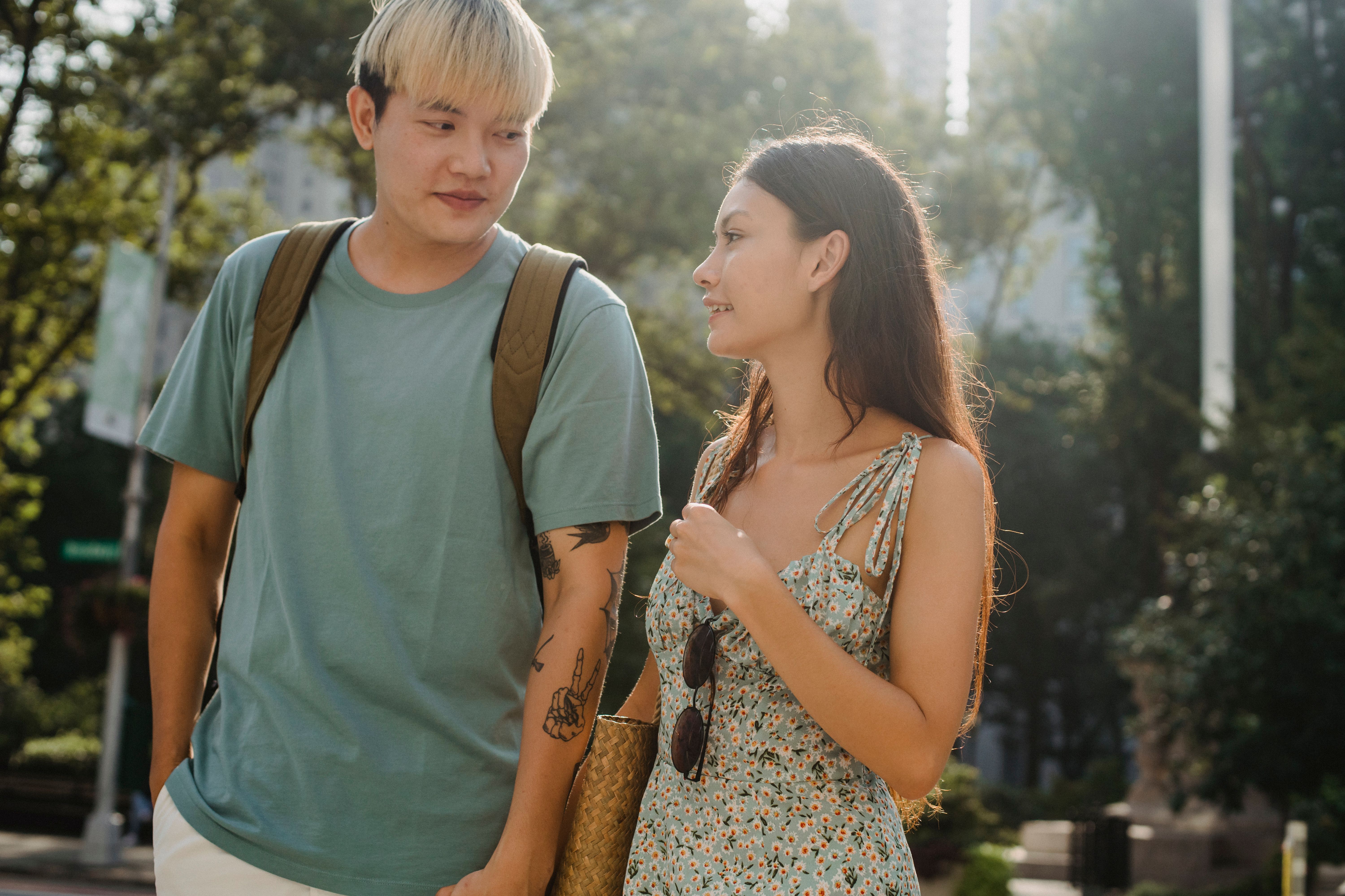 Positive multiracial couple holding hands while spending time together in sunny day in town