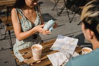 Crop ethnic couple with photo camera and takeaway coffee