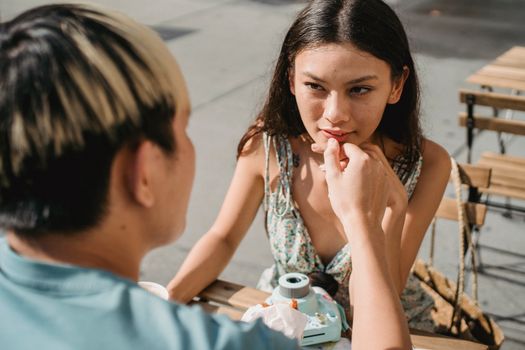 在街头咖啡馆的餐桌上，一位染着头发的匿名男子轻抚着心爱女子的手，两人相视而望