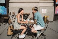 一对年轻夫妇在阳光明媚的早晨，于户外享受咖啡约会，微笑着交谈