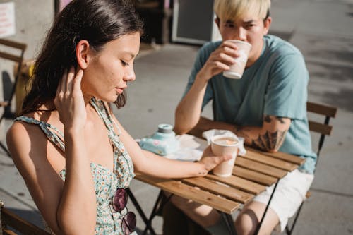 Серьезная многорасовая пара пьет кофе в уличном кафе