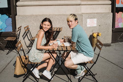 Cheerful multiracial couple resting with coffee at table