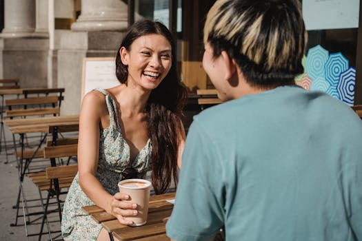 Two friends enjoying a sunny day, chatting over coffee at an outdoor cafe.
