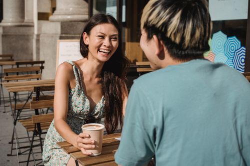 Free Happy friends laughing and enjoying coffee at table on street on sunny summer day Stock Photo