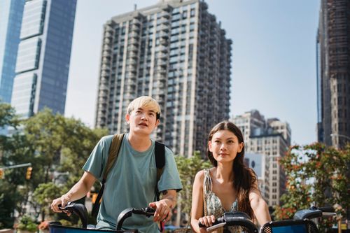 Free From below of calm multiracial couple riding bicycles in modern residential district in city in daytime Stock Photo