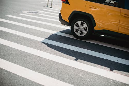 Free Contemporary yellow car driving on pedestrian crossing on city street in sunny day Stock Photo