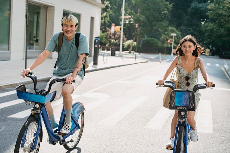 Positive Couple Riding Bicycles On Street In City