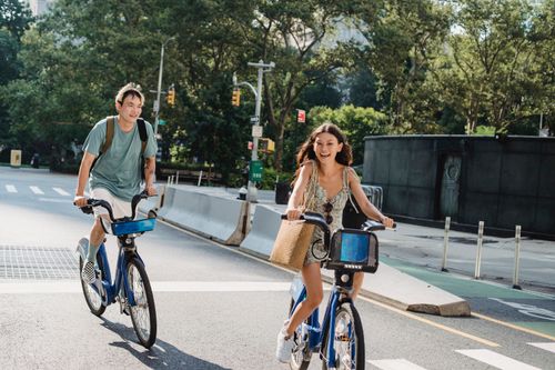 Free Cheerful diverse couple laughing and riding bicycles on asphalt road in city in sunny day Stock Photo