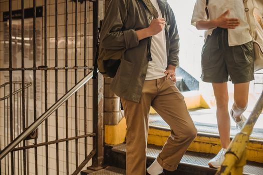 Crop anonymous couple in stylish outfits walking downstairs together in underground pedestrian passage