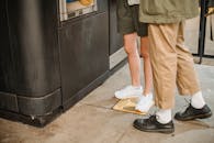 一对休闲打扮的情侣站在城市时尚街区的自动售货机旁，专注地看着鞋类商品