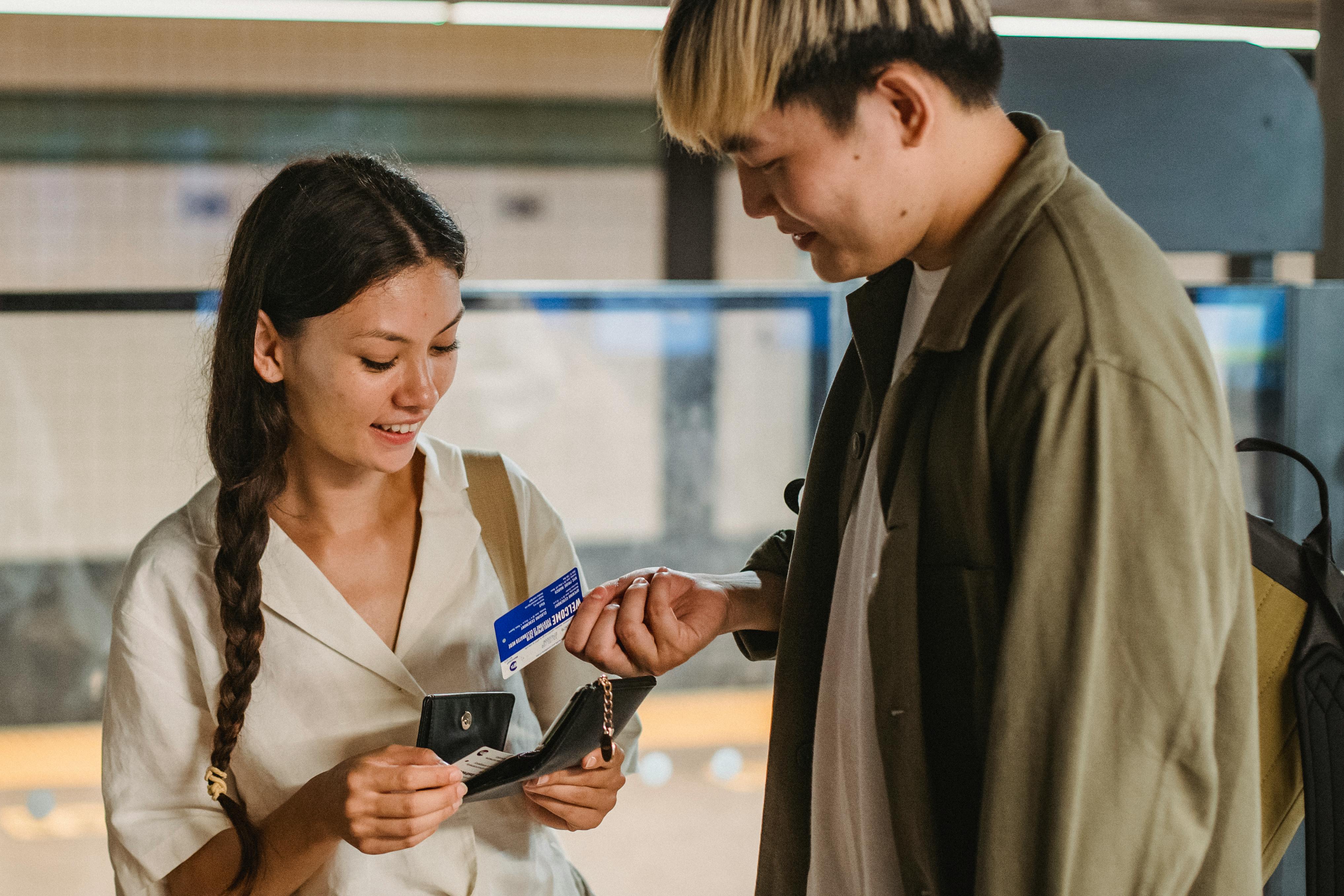 positive asian couple buying subway tickets