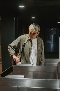 Calm Asian male in casual clothes swiping ticket and passing through turnstile in underground