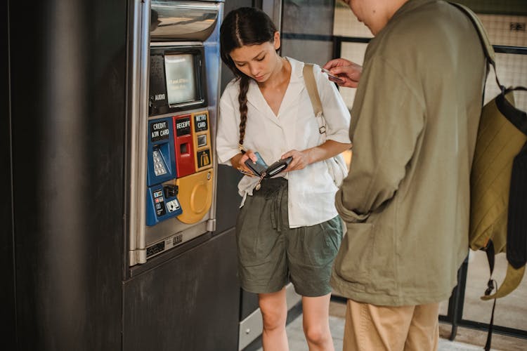 Couple Standing Near Ticket Machine And Opening Wallet