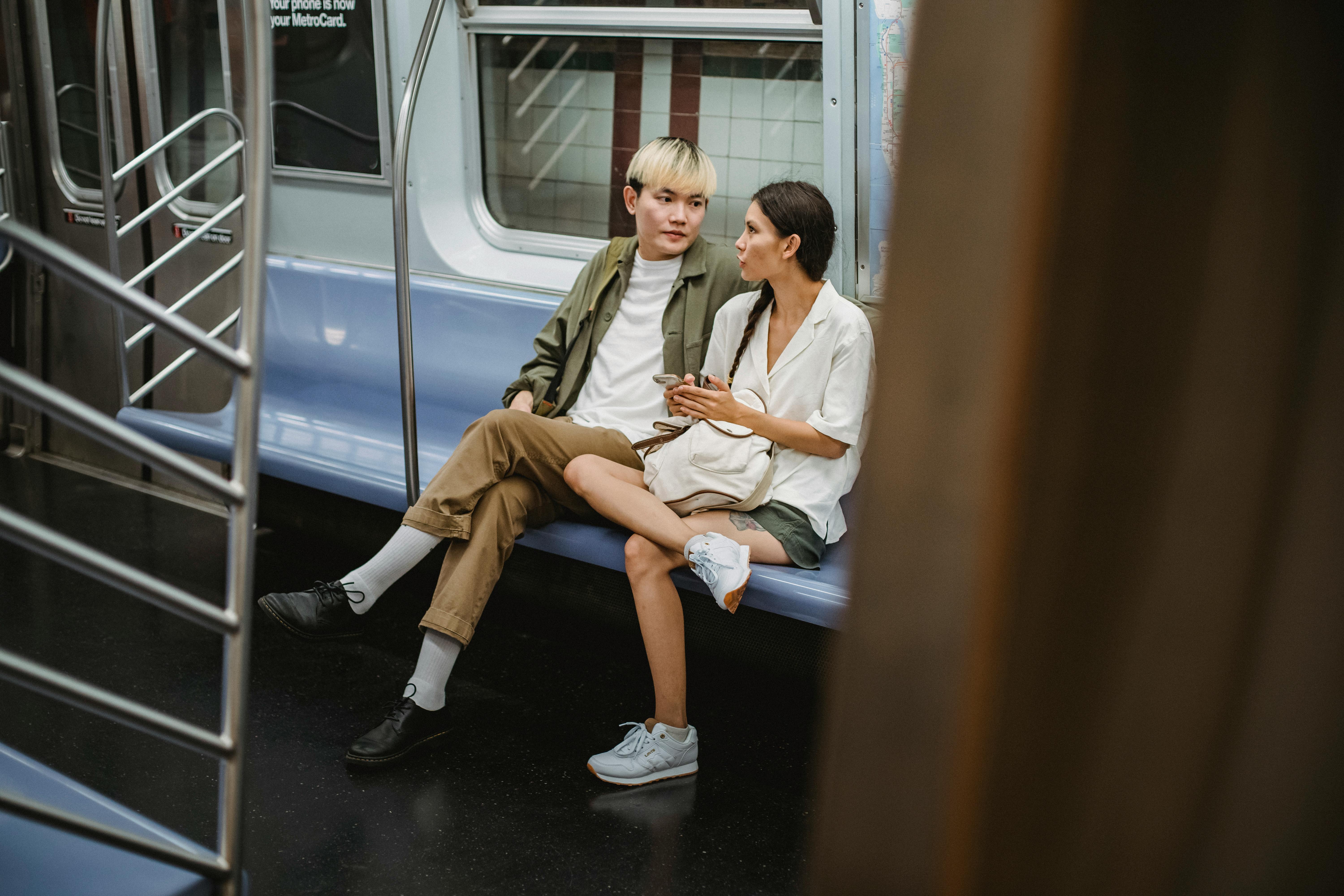 trendy young asian couple looking at each other while riding train