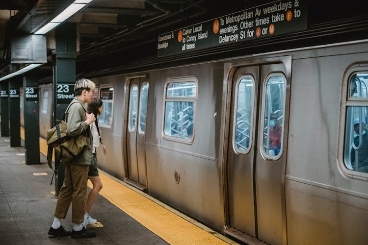 Young Couple Standing In Front Of Train On Metro Station Platform