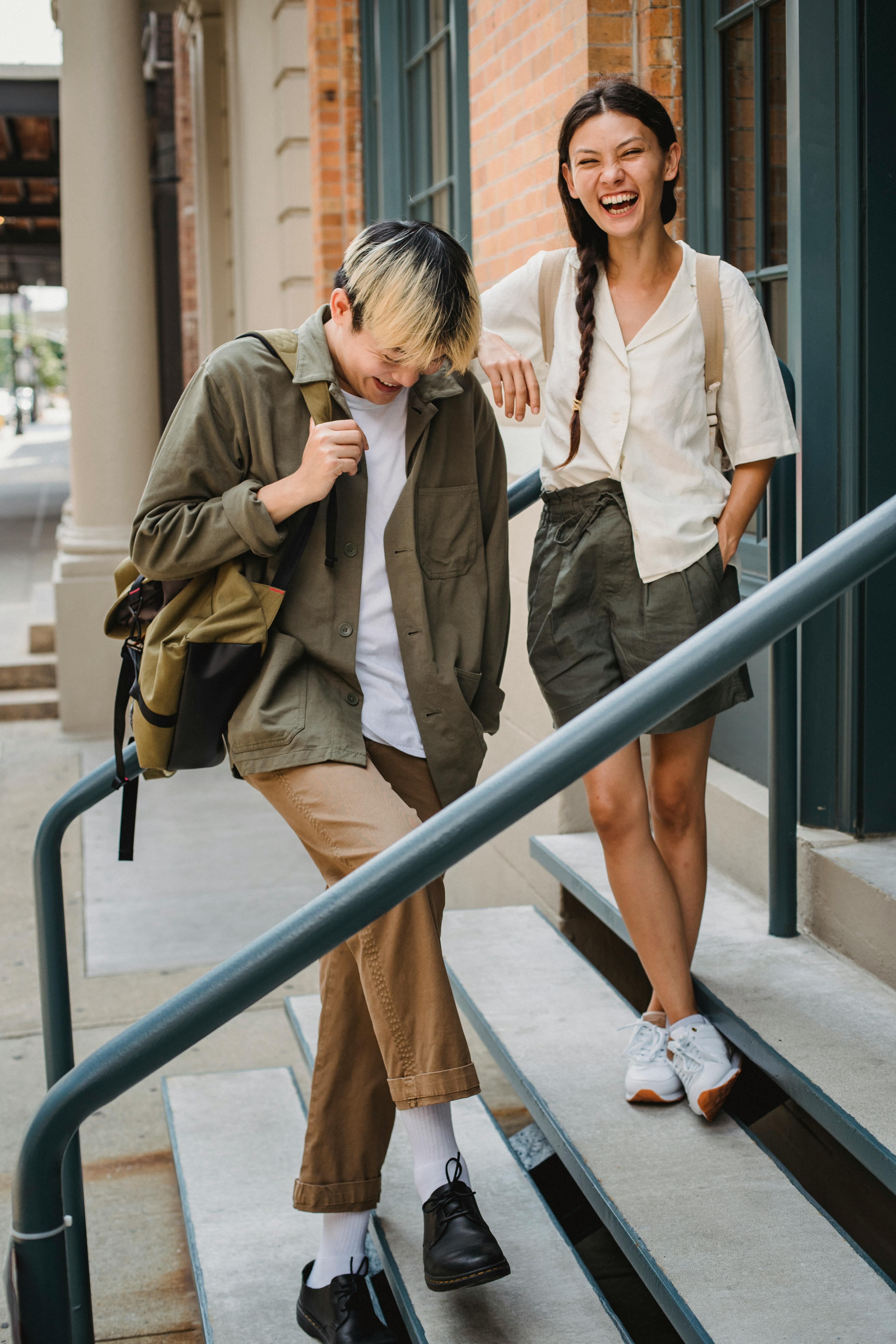 joyful young ethnic couple laughing on building stairs