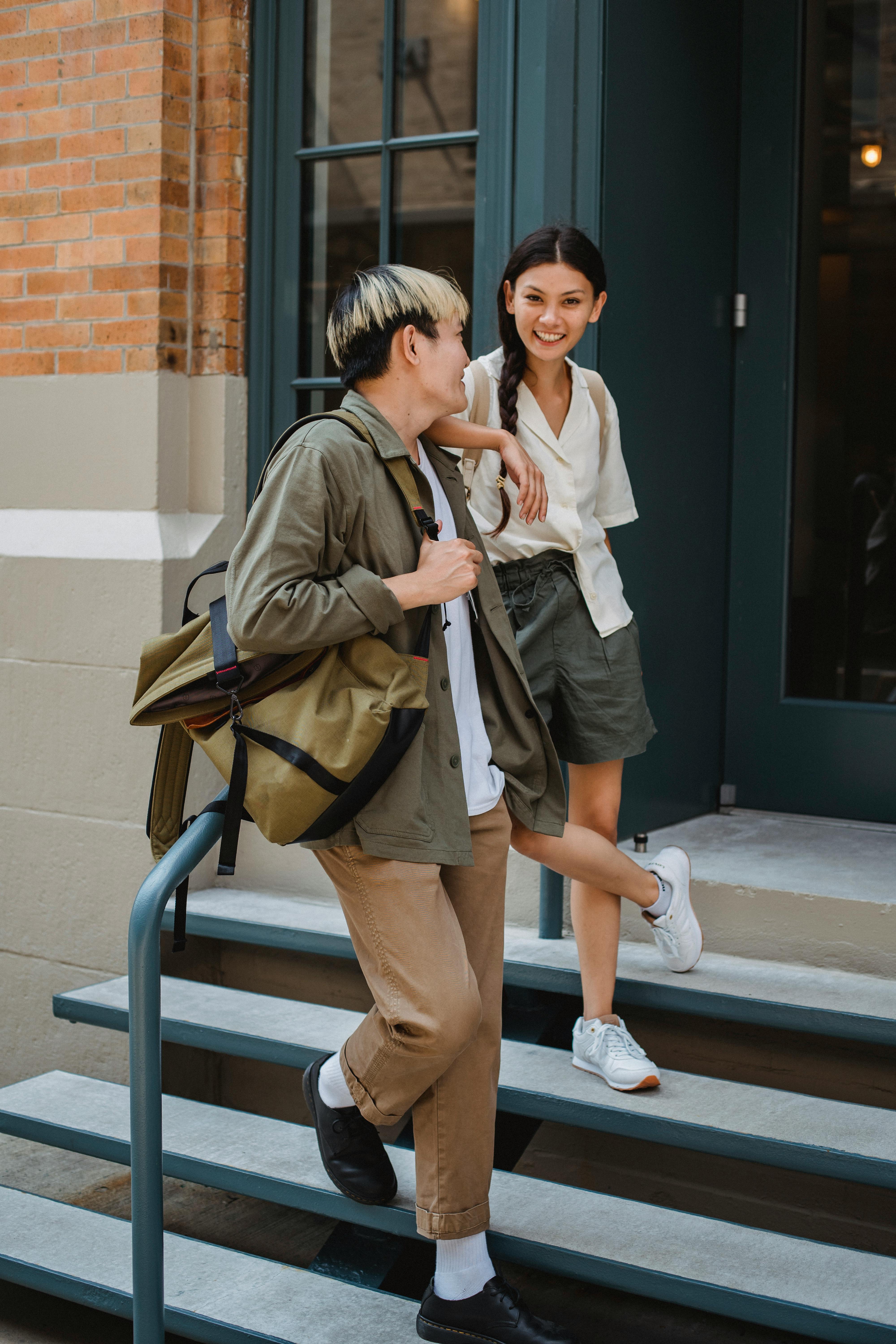 trendy asian couple chilling on building stairs on street