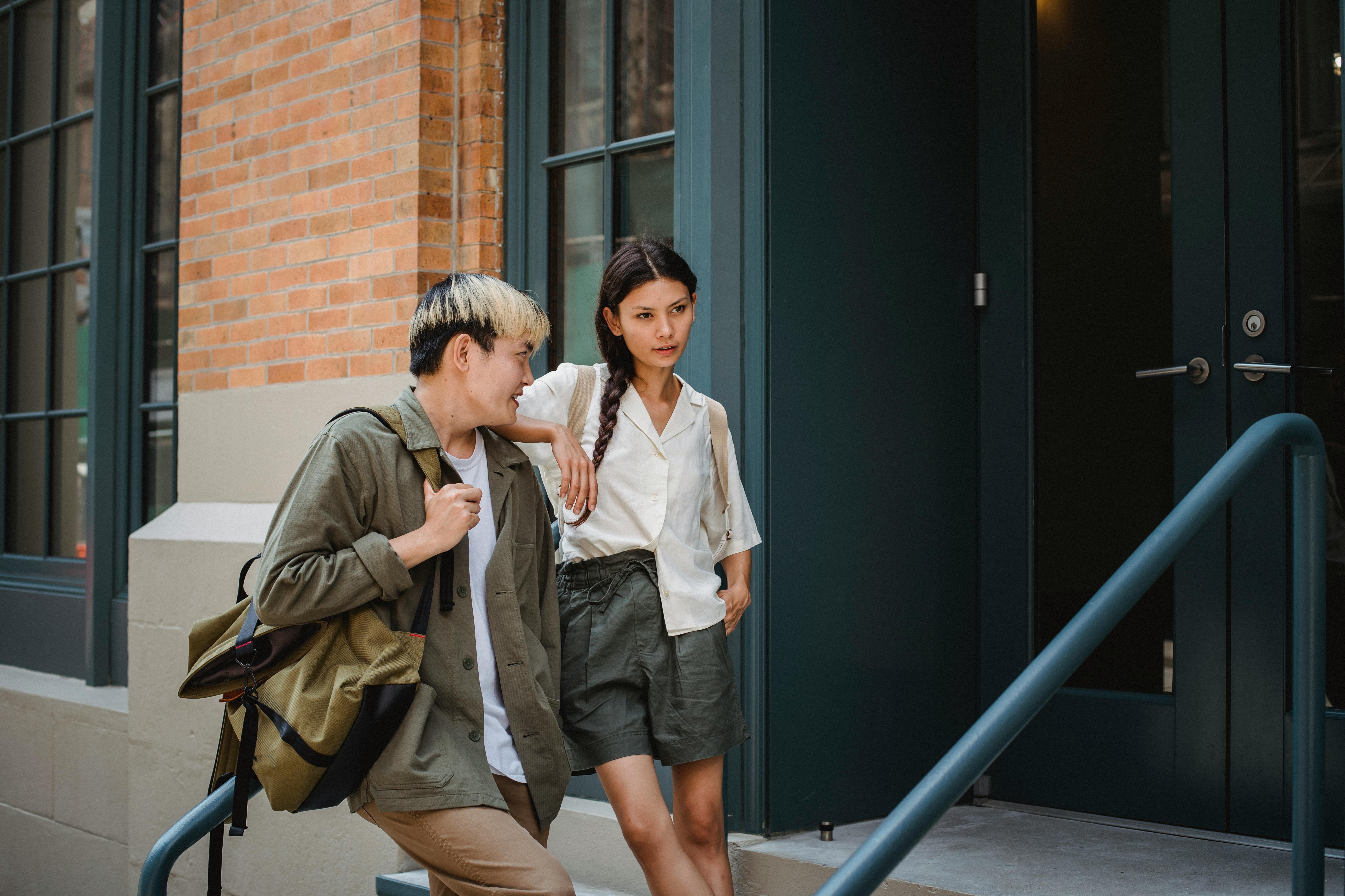 stylish asian couple standing near modern building entrance