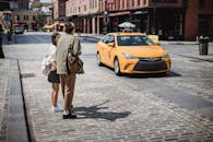 一对穿着时尚夏装的情侣手牵着手，站在阳光明媚的城市路边