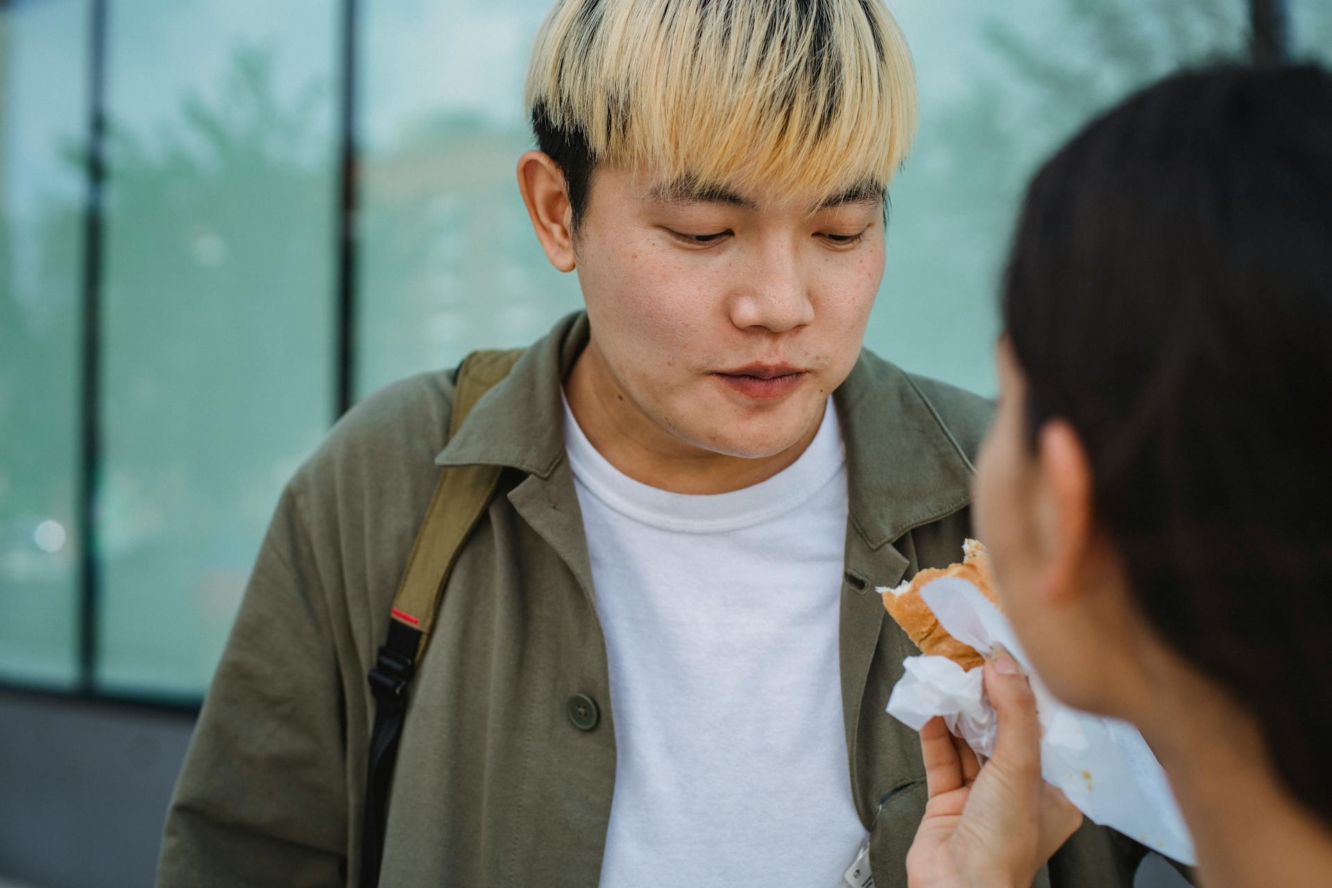 Woman hand feeding Asian boyfriend with hot dog