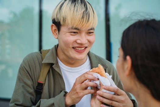 Smiling couple sharing a delicious street food snack outdoors.