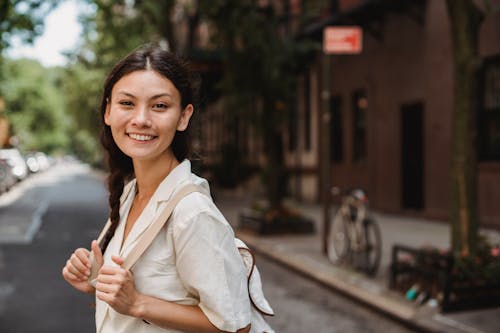 Smiling ethnic woman standing on city street