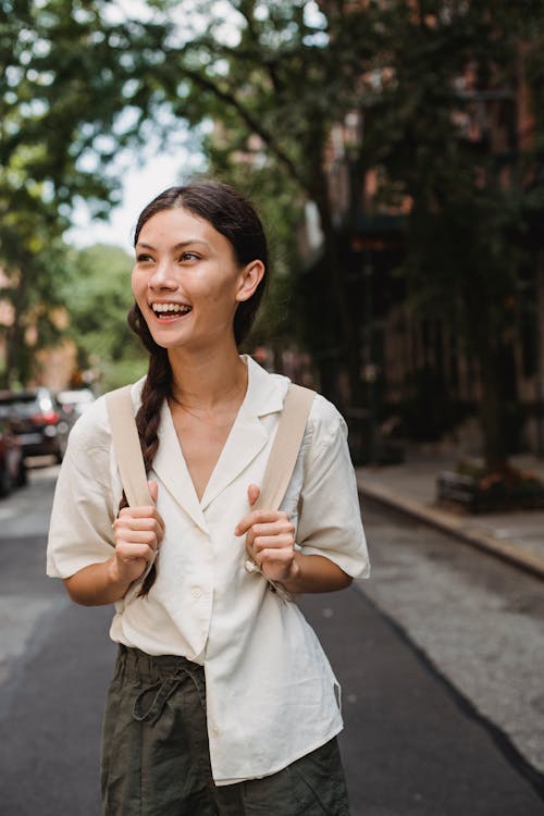 Joyful ethnic woman standing on sunny town street