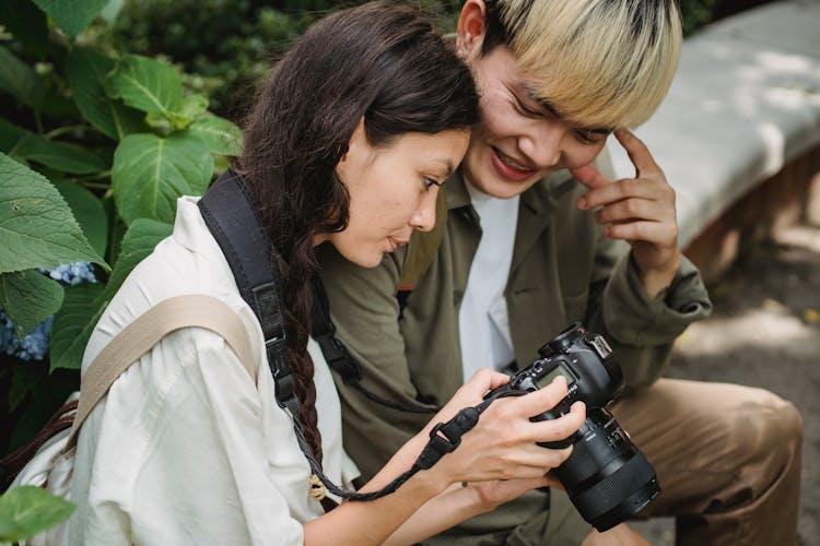 Cheerful Asian Couple Using Photo Camera In Park