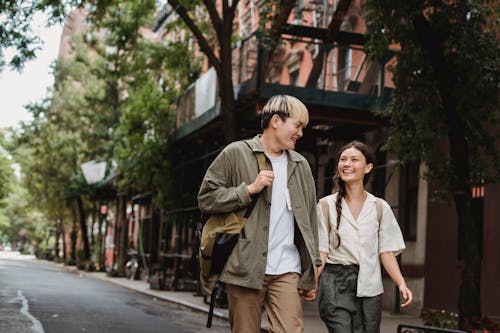 Cheerful multiethnic couple talking while walking on city street