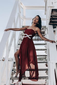 一位身穿红色时尚连衣裙的女子在户外楼梯上摆出优雅的姿势