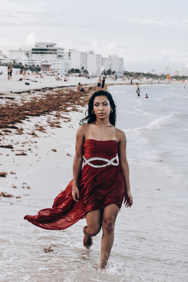 Attractive Ethnic Woman In Chic Dress Walking On Sandy Beach