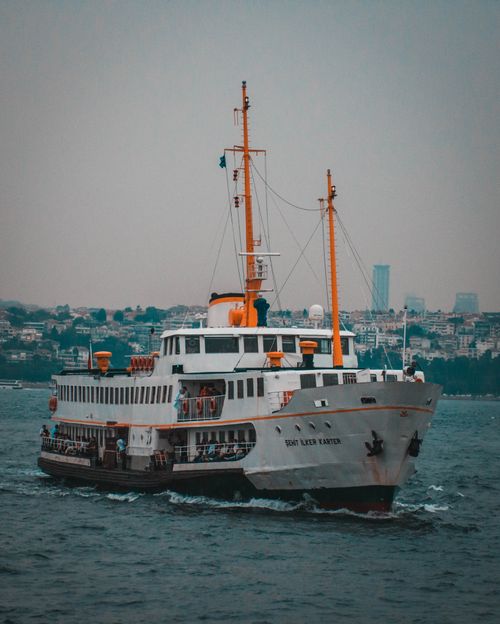 Free A large passenger ferry cruises through the sea with a cityscape background in a calm setting. Stock Photo