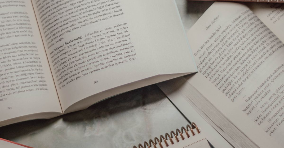 A collection of open books and a spiral notebook on a study table, creating a literary ambiance.