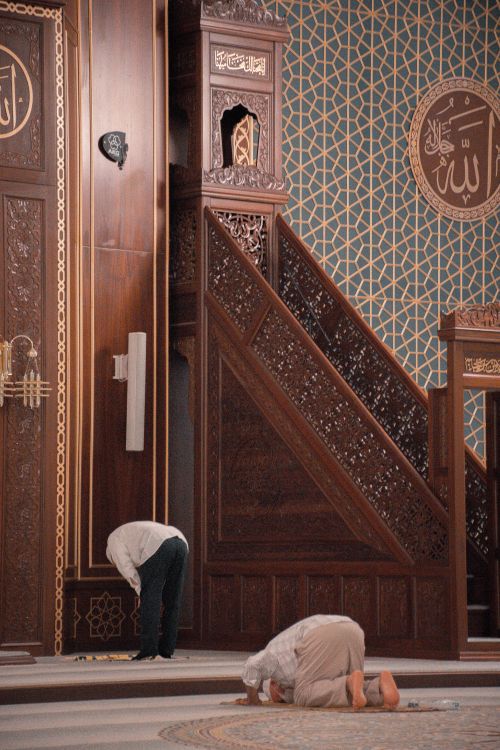 Free Two men engaged in prayer within a beautifully ornate mosque interior, showcasing intricate Islamic art and design. Stock Photo