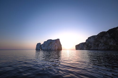 Majestic landscape of chalk cliffs in rippling sea water against cloudless sundown sky