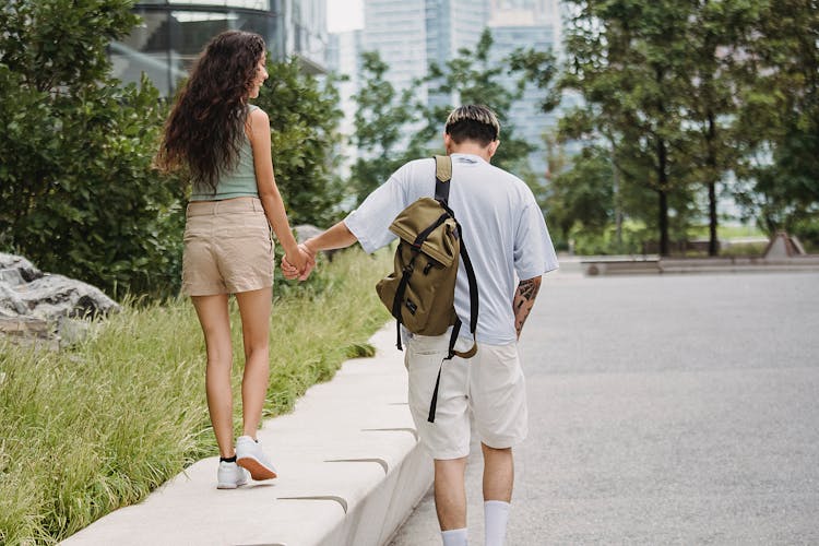 Stylish Young Couple Holding Hand And Walking In City Park