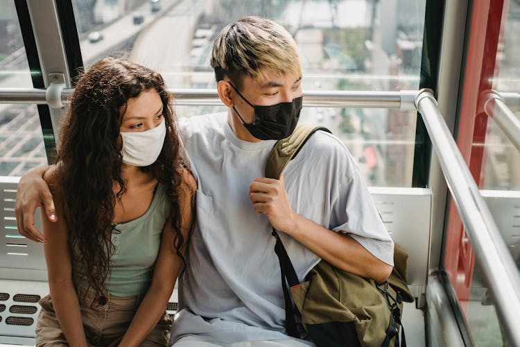 Diverse Couple In Masks Hugging In Funicular