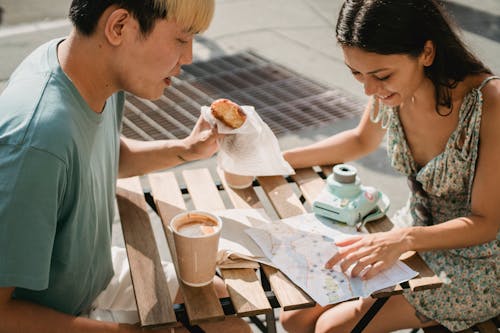 Free Diverse couple having breakfast in cafe while exploring map Stock Photo