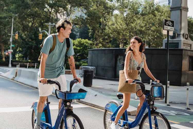 Cheerful Asian Couple Riding Bicycles On Street