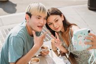Cheerful Asian couple taking selfie in cafe