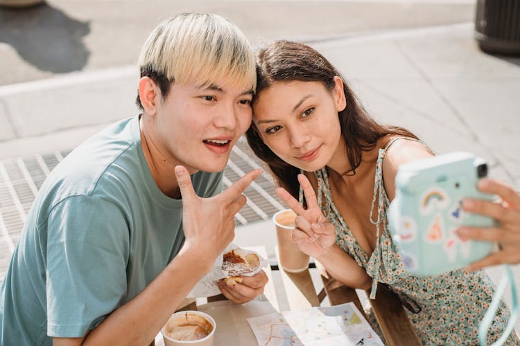 Cheerful Asian Couple Taking Selfie In Cafe