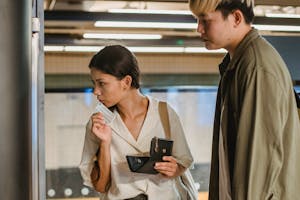 Focused Asian couple buying ticket on station
