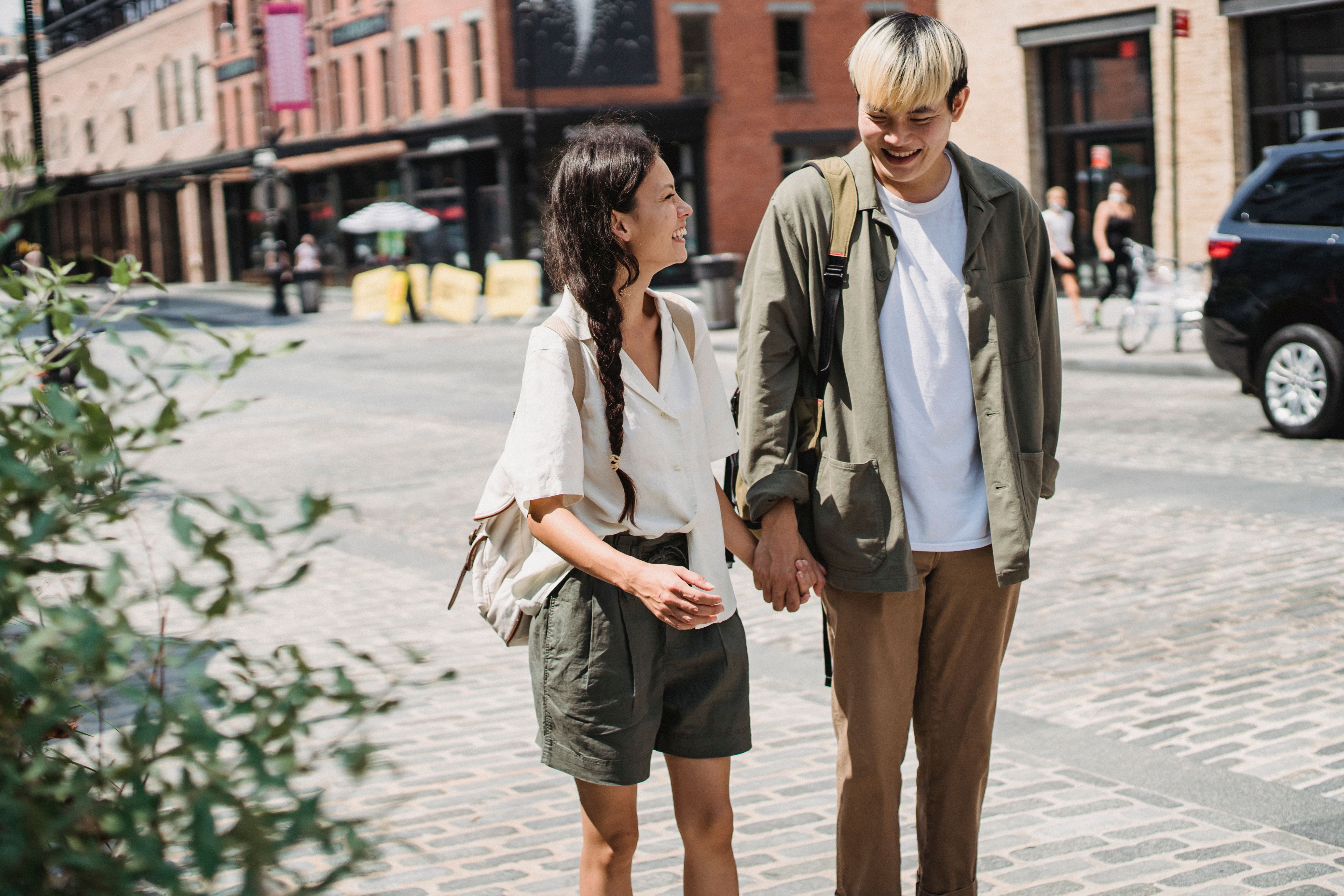 delighted asian couple walking on sidewalk