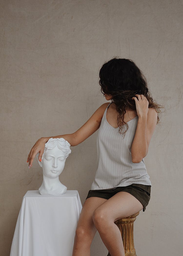 Anonymous Woman In Trendy Outfit Near Stone Bust