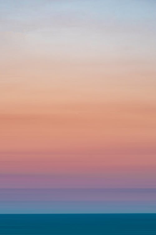 Light blue pink sky over silent ocean at sunset