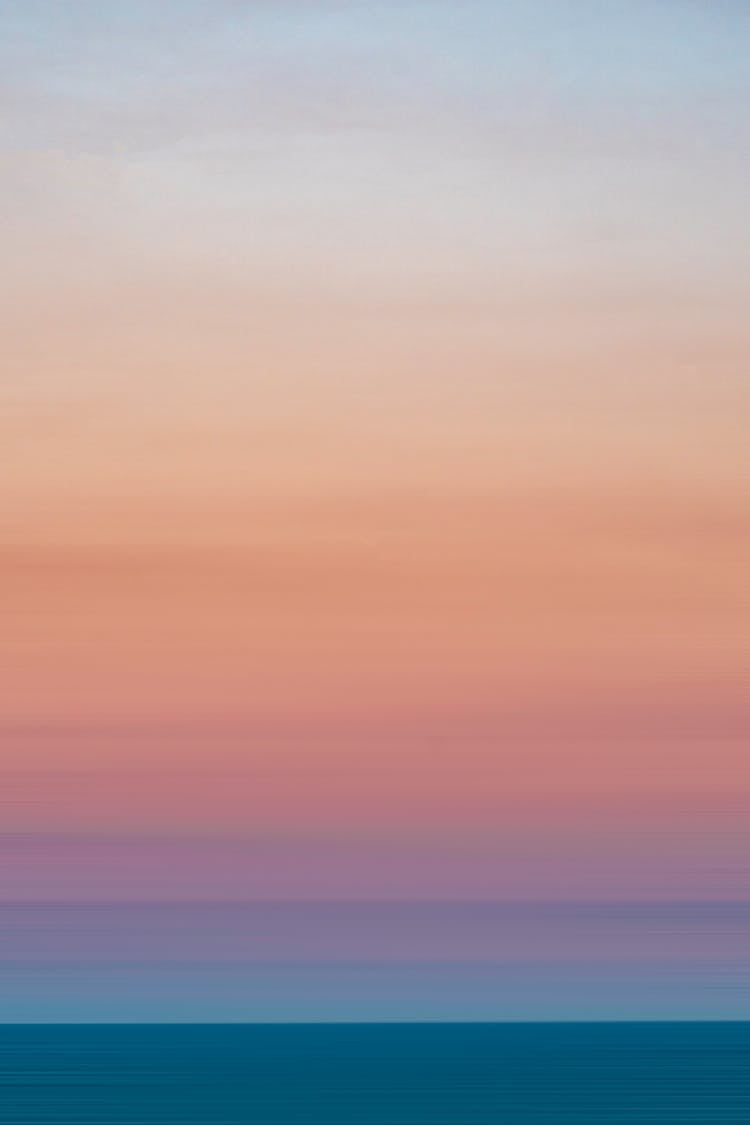 Light Blue Pink Sky Over Silent Ocean At Sunset