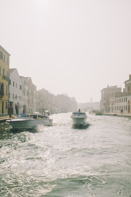 Idyllic scene of boats on a canal in Venice, capturing the serene misty atmosphere of the city.