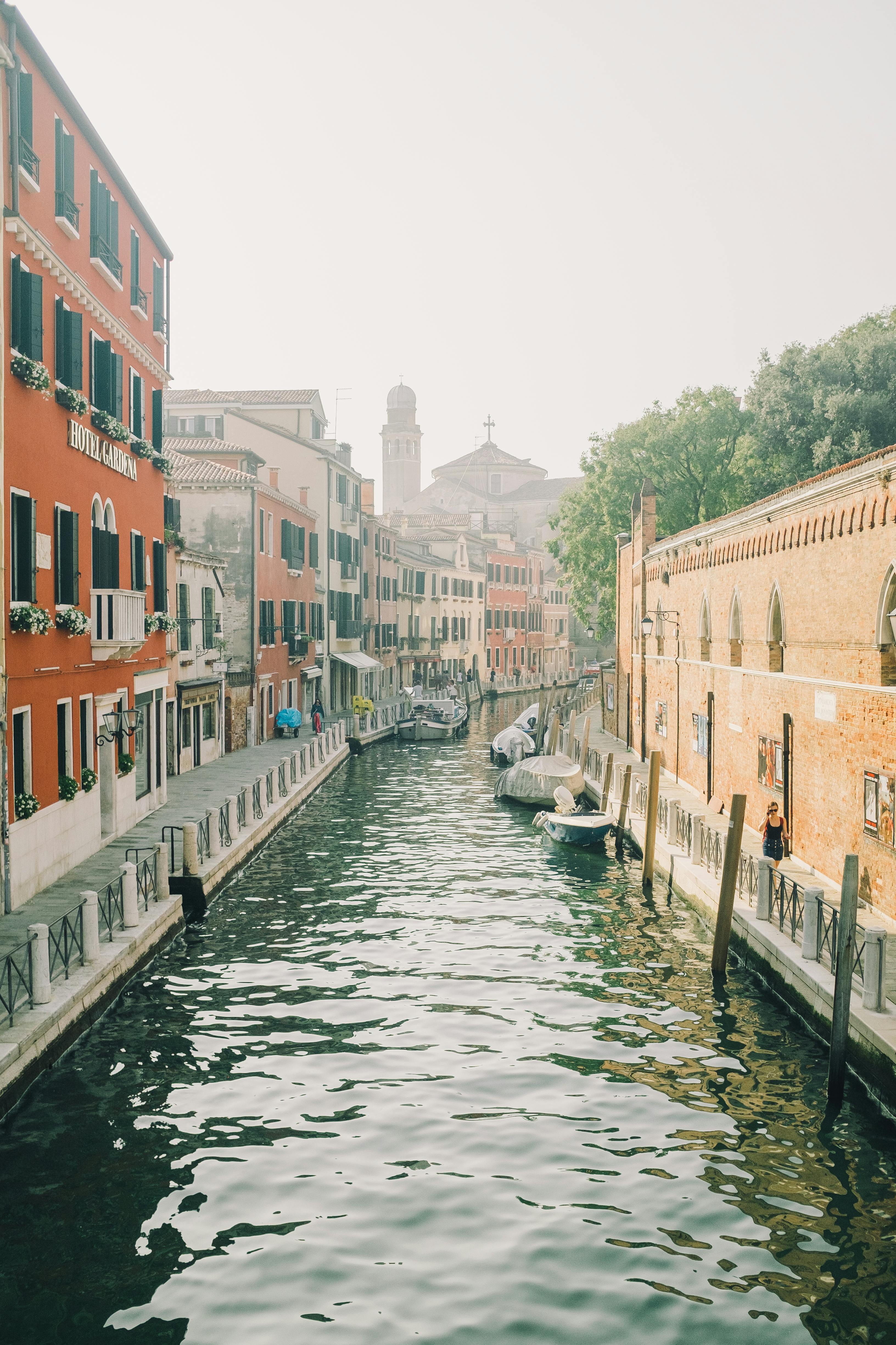 boats on canal between buildings